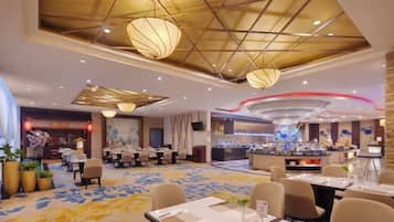 A hotel dining area with tables, chairs, and a buffet.