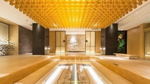 A spacious lobby with a central marble floor, wooden benches, and a unique ceiling design. - Zhuozheng International Hotel (Baoding)