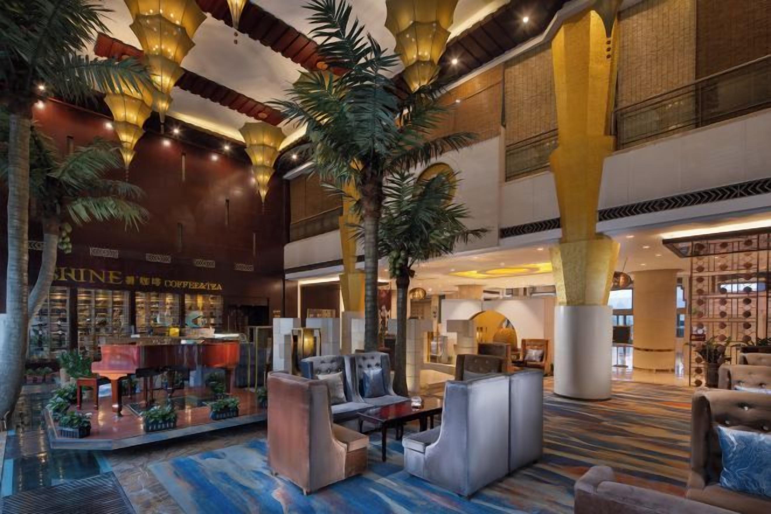 A spacious lobby with seating areas, a coffee shop, and a large decorative plant.