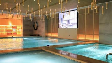 An indoor swimming pool with multiple lanes, a projection screen, and a wooden ceiling.