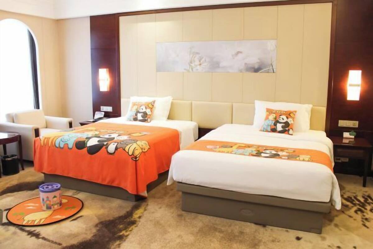 Habitación de hotel con dos camas, un sofá, una mesita y una alfombra con un diseño de dibujos animados.