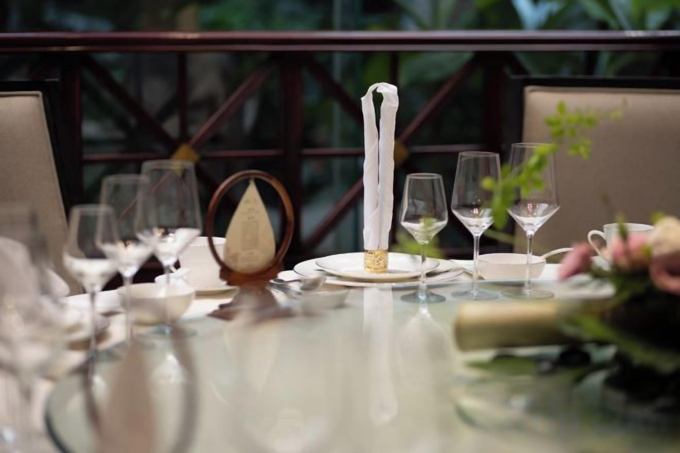 A dining table set with plates, glasses, and a centerpiece.