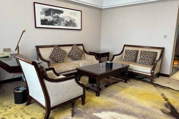 A living room with a sofa, armchairs, a coffee table, and a framed artwork on the wall. - Zhuozheng International Hotel (Baoding)