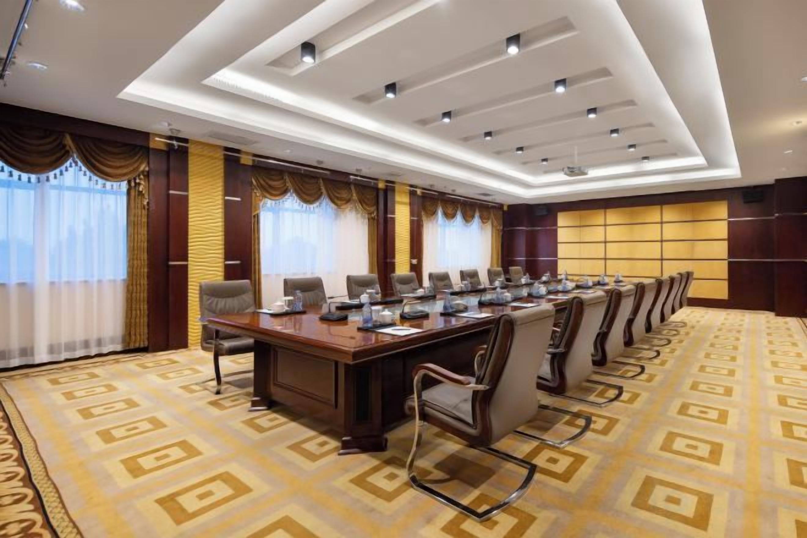 A conference room with a long table, chairs, and a carpeted floor.