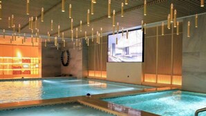 A modern indoor swimming pool with multiple lanes, a sauna area, and a projection screen displaying a building model. - Zhuozheng International Hotel (Baoding)