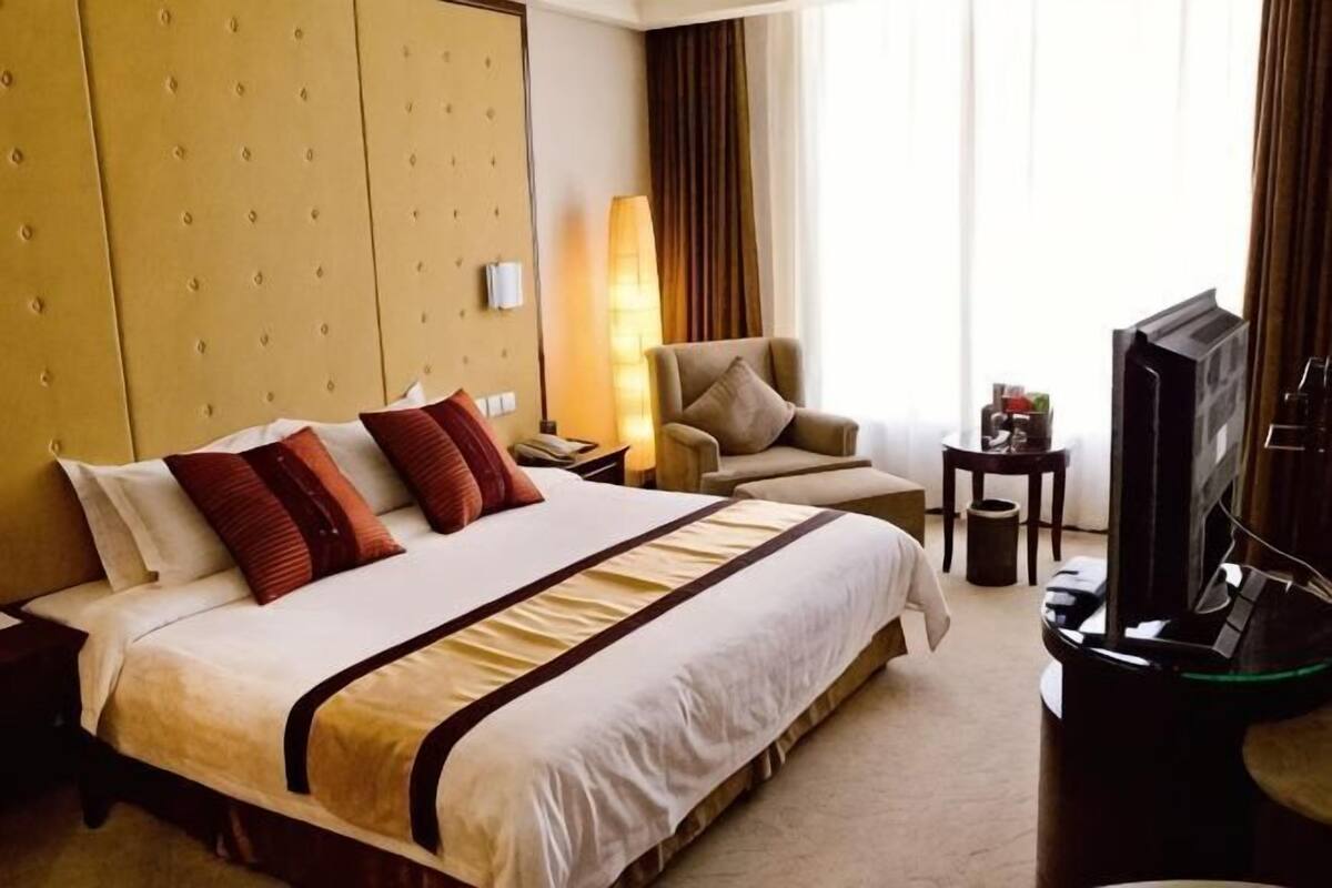 Habitación de hotel con una cama grande, un sofá, un televisor y un escritorio.