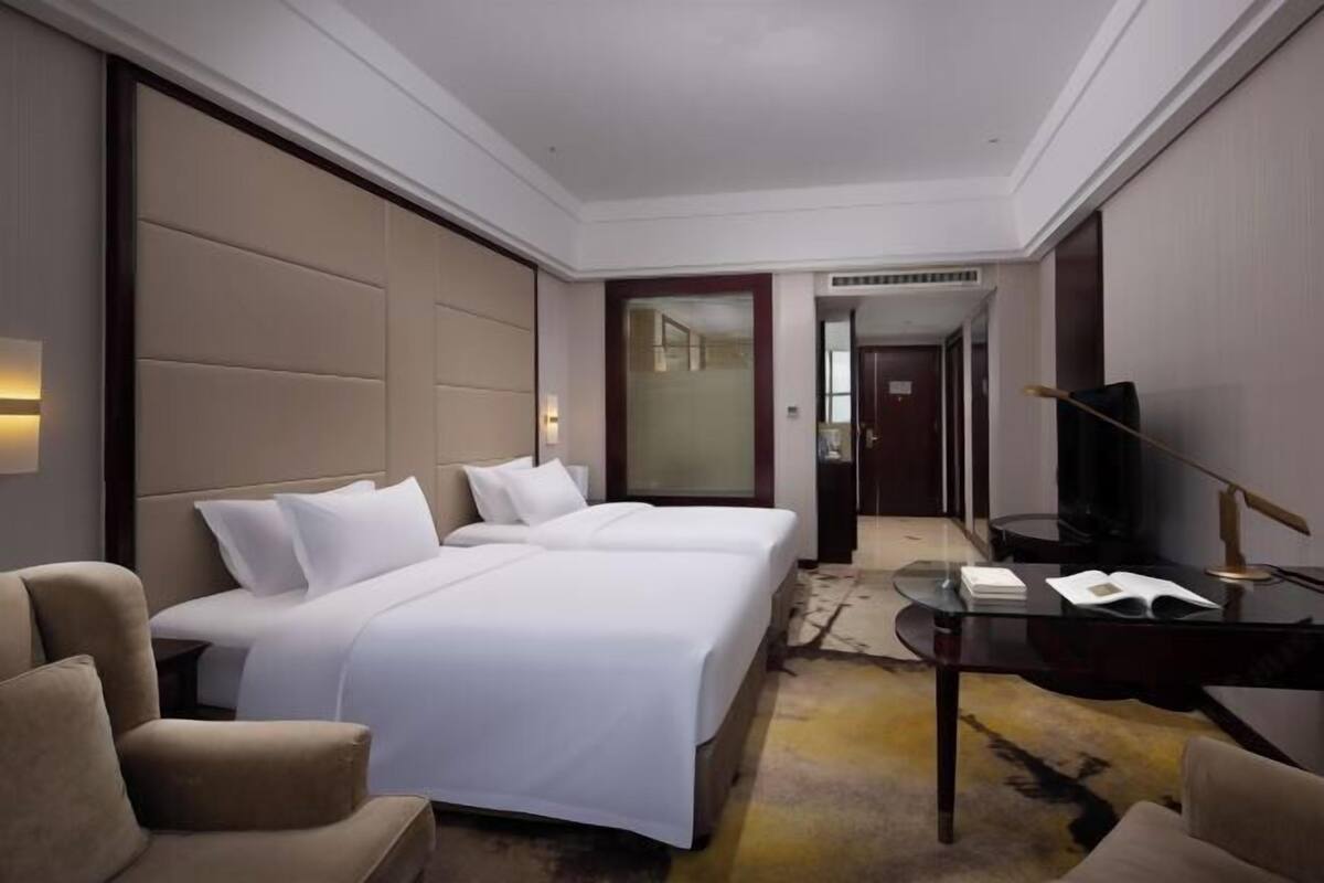 Una habitación de hotel con dos camas, un escritorio, una silla y un televisor.