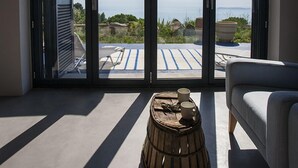 Ein modernes Zimmer mit großen Schiebegläsern, die auf eine Terrasse mit Meerblick führen.