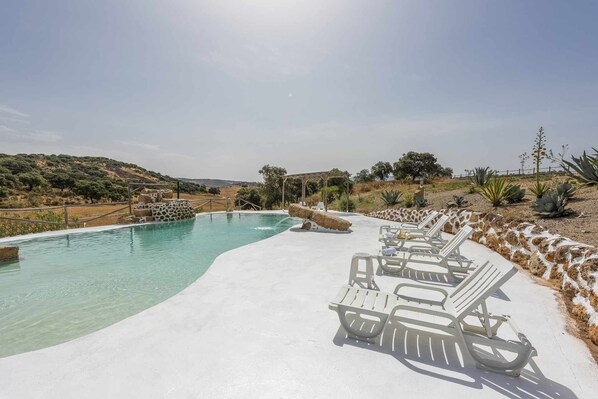 A pool area with lounge chairs and a pergola.