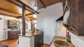 A rustic kitchen with wooden beams, a stone sink, and a microwave on the counter. - El Ventorrillo Cottage, in Morón de la Frontera (Moron De La Frontera)