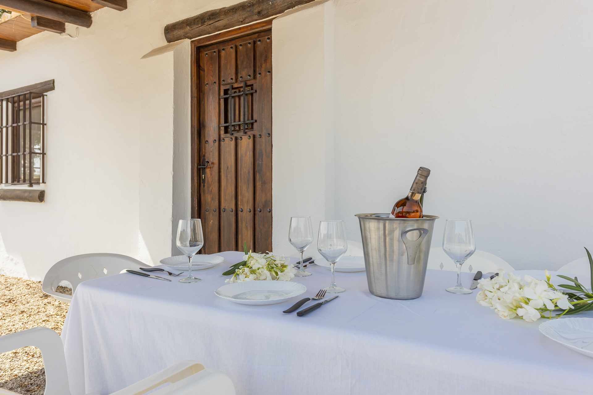 Una mesa lista para una comida, con una botella de vino, copas, platos y cubiertos.