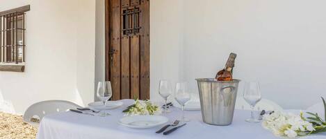 Una mesa lista para una comida, con una botella de vino, copas, platos y cubiertos.