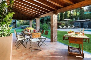 An outdoor patio with a wooden pergola, a brick column, and a dining table set for six. - Villa Granvia - Private villa with pool in Sicily (Trecastagni)