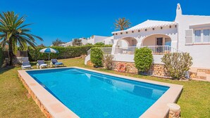 A poolside view of a white villa with a clear blue pool, surrounded by greenery and palm trees. - Binire · Villa BiniRe ❤️ private pool ❤️ Free AC/Wifi (Binibequer)