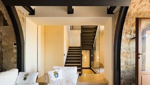 Un salon moderne avec un escalier, des canapés blancs et une table basse en verre.