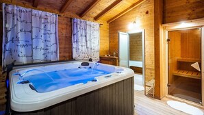 L’intérieur d’un chalet en bois comprend un bain à remous, un sauna et une salle de bain avec un miroir.