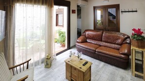 A living room with a brown leather sofa, a wooden coffee table, a striped armchair, and a view of the outside through a glass door.