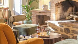 A cozy living room with a stone fireplace, comfortable seating, a table with a bottle and glasses, and a potted plant. - Villa Amiata - Tuscan Farmhouse with private pool (Castel del piano)