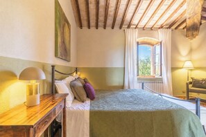 Ein Schlafzimmer mit einem Bett, Nachttischlampen, einem Fenster mit Vorhängen und einem Bild an der Wand.