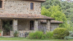 A stone building with a tiled roof, a small porch with chairs, and a garden. - Villa Amiata - Tuscan Farmhouse with private pool (Castel del piano)