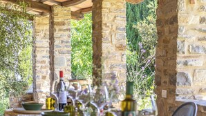 A stone-walled outdoor dining area with a table set for a meal, surrounded by greenery and a view of trees. - Villa Amiata - Tuscan Farmhouse with private pool (Castel del piano)