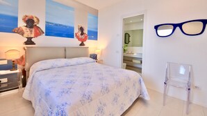 Un dormitorio con una cama, dos lámparas de pared, una silla transparente y dos bustos en la pared.