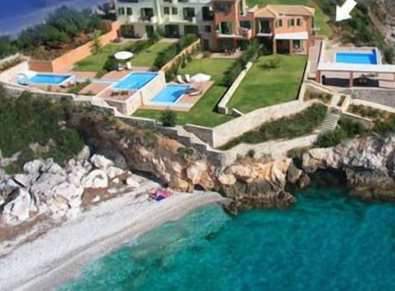 A coastal villa with a house and a suite, featuring a swimming pool and rocky terrain.