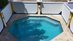 A swimming pool with a tiled deck and a white umbrella.