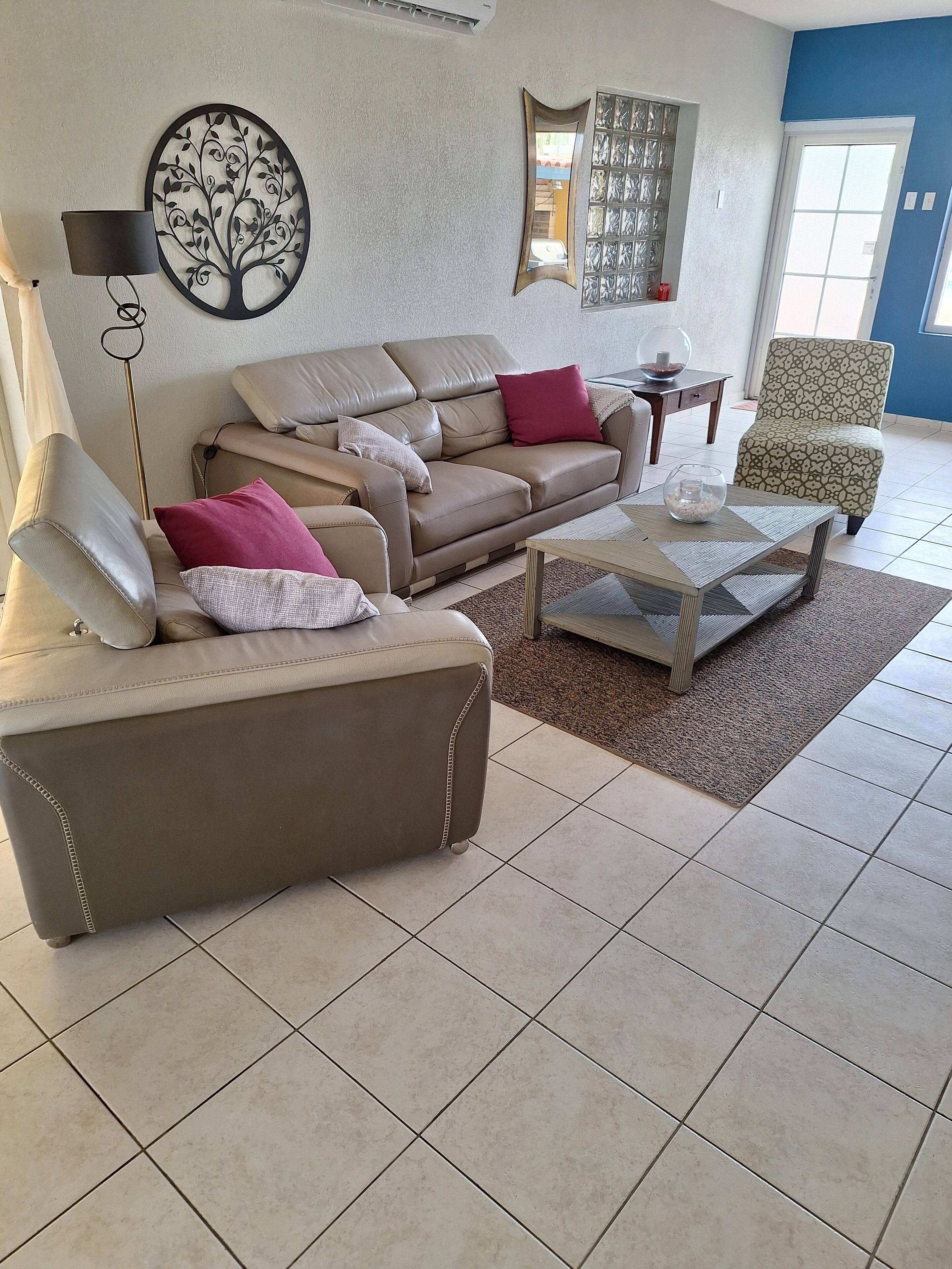 Ein Wohnzimmer mit einem beigen Sofa, einem Couchtisch und einem gemusterten Sessel.