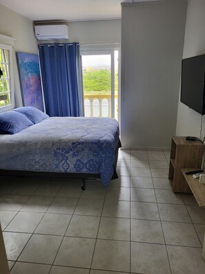 A bedroom with a bed, a TV, and a balcony with a view. - Savaneta Beachfront + Private pool Savaneta (Savaneta)