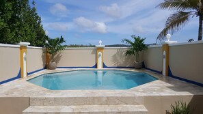 A swimming pool with a tiled deck, surrounded by walls with decorative moldings and potted plants. - Savaneta Beachfront + Private pool Savaneta (Savaneta)
