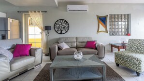 A living room with a sofa, a coffee table, and a patterned armchair.