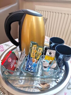 A tray with a coffee pot, packets of sugar, coffee creamer, and a spoon.