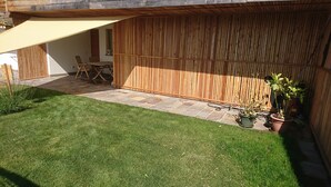 A patio area with a wooden fence, a table and chairs, and potted plants. - The window on the dolomites (Baselga di Pinè)