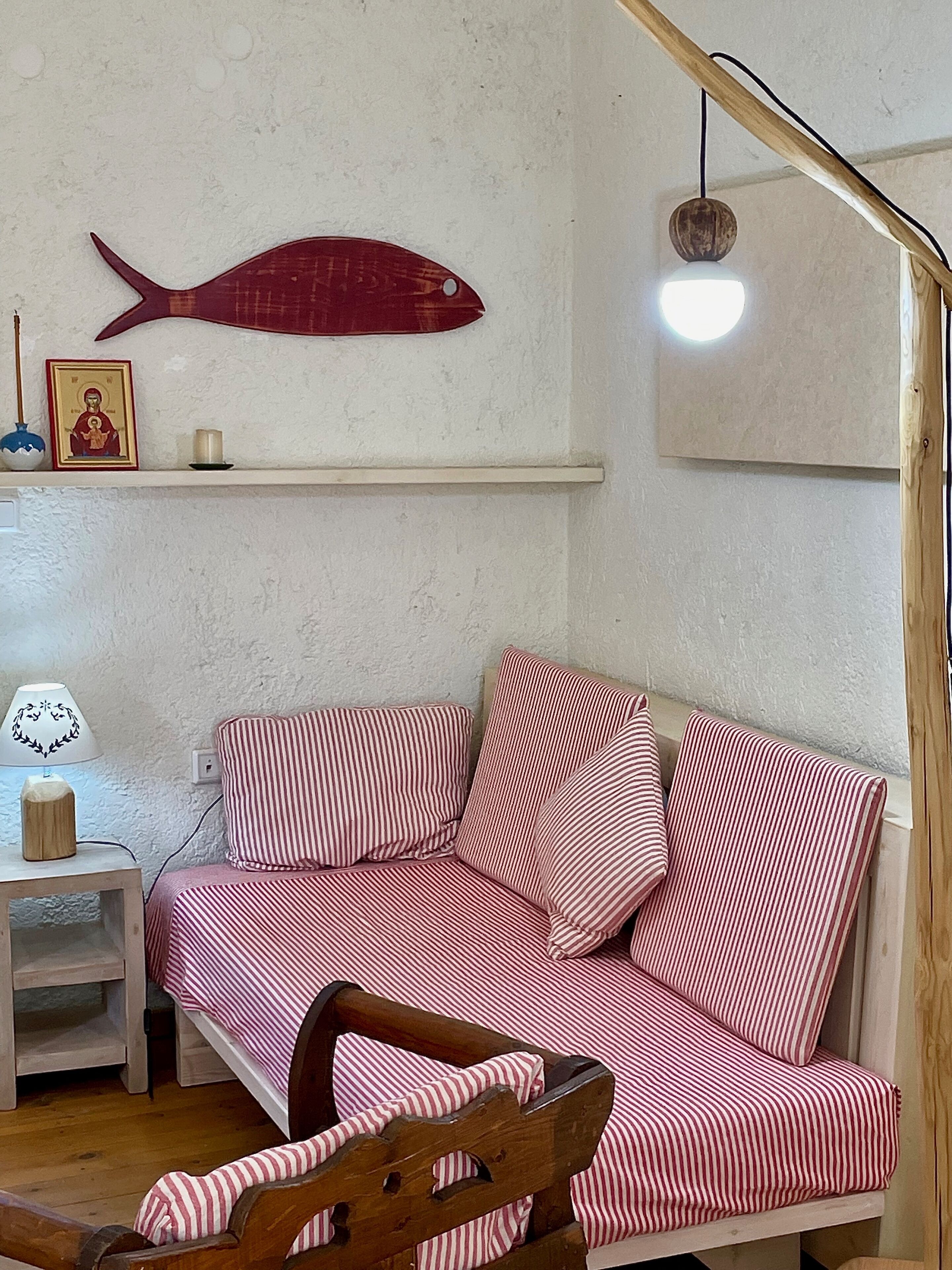 Una habitación acogedora con una cama de madera, una mesita con una lámpara, un estante con una decoración de pez y un aplique de pared.