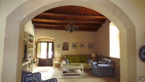 A living room with a high arched ceiling, a sofa set, a coffee table, and a bookshelf. - Villa Albero Limone Luxury 3 bedroom 4 bathooms farmhouse private pool and wif (Chiaramonte Gulfi)
