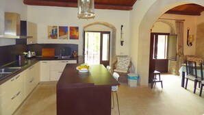 A kitchen with a central island, wooden ceiling, and a dining area with a table and chairs. - Villa Albero Limone Luxury 3 bedroom 4 bathooms farmhouse private pool and wif (Chiaramonte Gulfi)