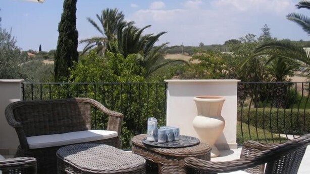 A balcony with wicker furniture, a large vase, and a view of greenery and distant hills. - Villa Albero Limone Luxury 3 bedroom 4 bathooms farmhouse private pool and wif (Chiaramonte Gulfi)