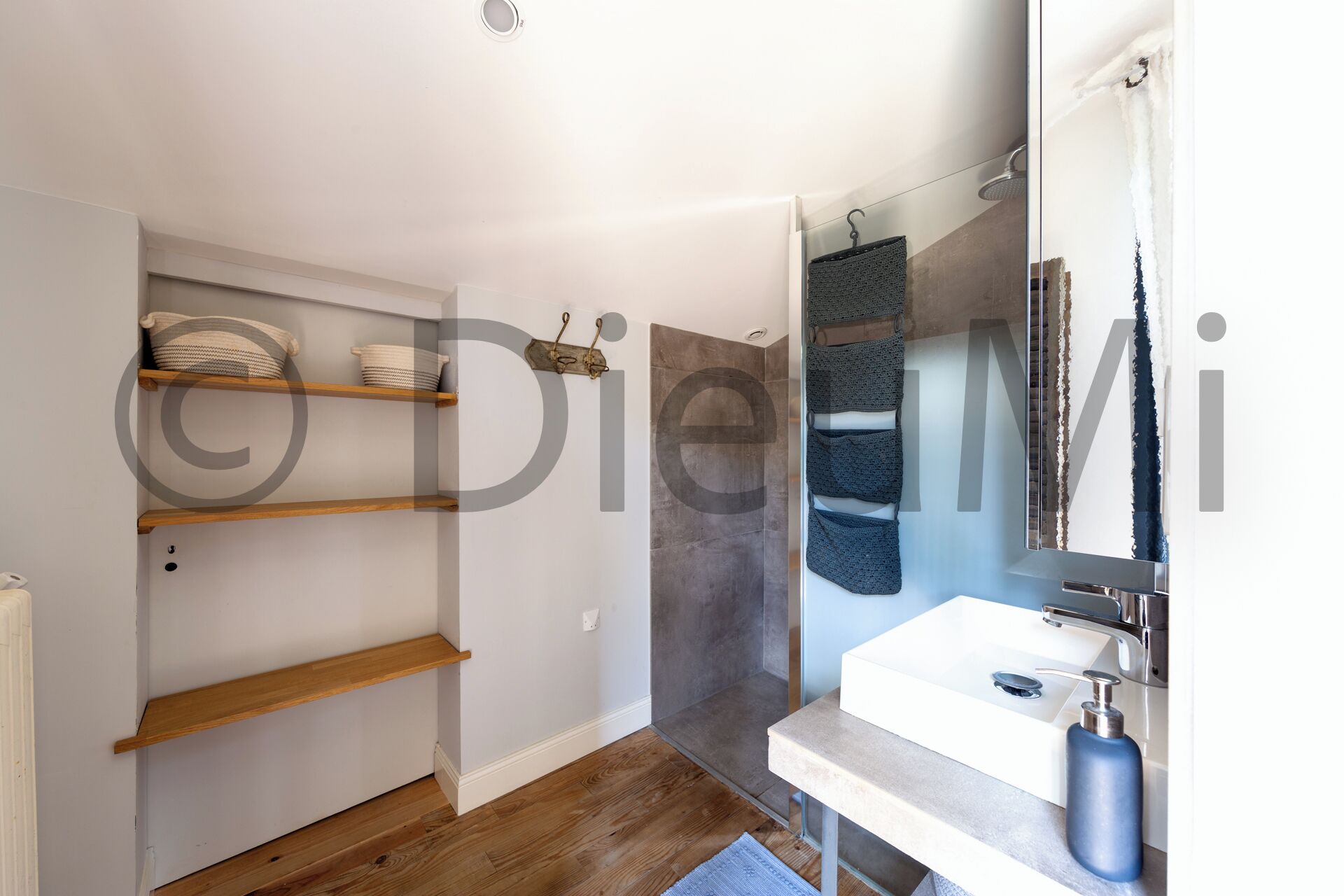 Un bagno moderno con doccia, lavandino e mensole in legno.
