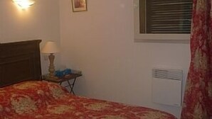 A bedroom with a bed, a nightstand, a lamp, a radiator, and a window with blinds. - Villa w/Lg Private Pool In Beautiful Languedoc-Roussillon Countryside-WiFi (Durban-Corbières)