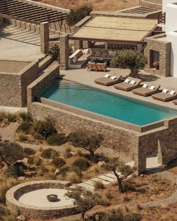 A pool area with lounge chairs and a stone wall.