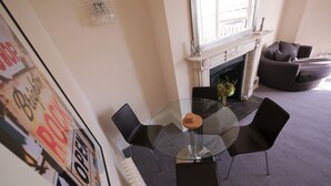 A dining area with a glass table surrounded by black chairs, a fireplace, and a sofa in the background. - Regency Retreat  - Stylish Apartment with sea views and balcony. Great Location. (Brighton)