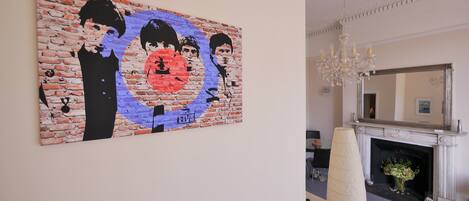 Una habitación con un cuadro de pared con diseño de ladrillos, una chimenea y una araña.