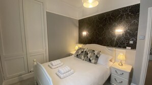 A neatly arranged bedroom with a large bed, two bedside tables, and a dark patterned wall. - Regency Retreat  - Stylish Apartment with sea views and balcony. Great Location. (Brighton)