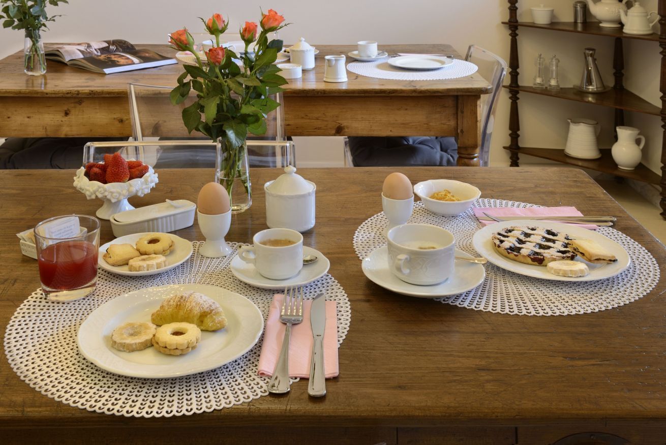 Une table dressée pour le petit-déjeuner, avec des assiettes de viennoiseries, du café et un saladier de fruits.