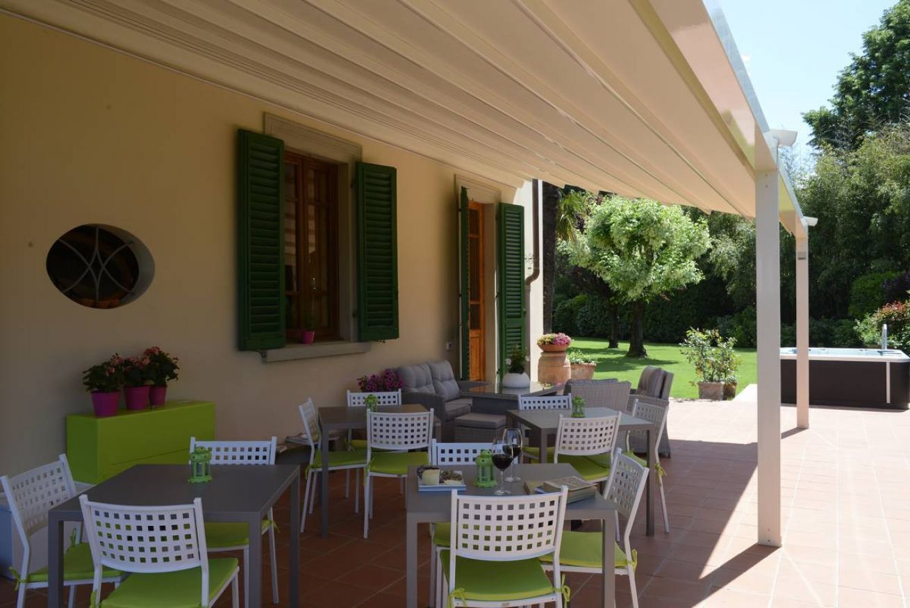 Un patio exterior con mesas y sillas, un sofá y una pérgola.