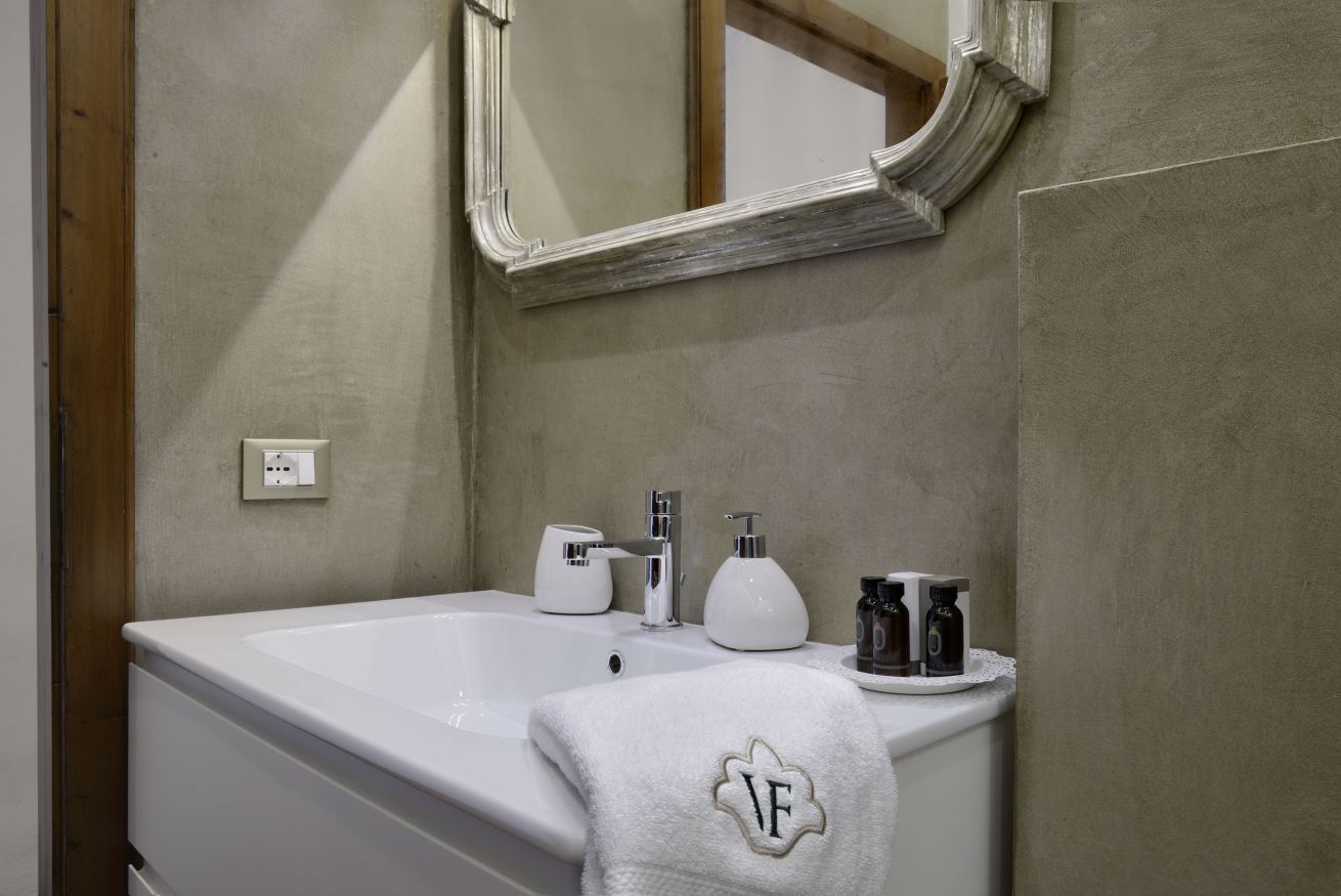 Un baño con una bañera blanca, un espejo sobre el lavabo y artículos de aseo en el lavamanos.