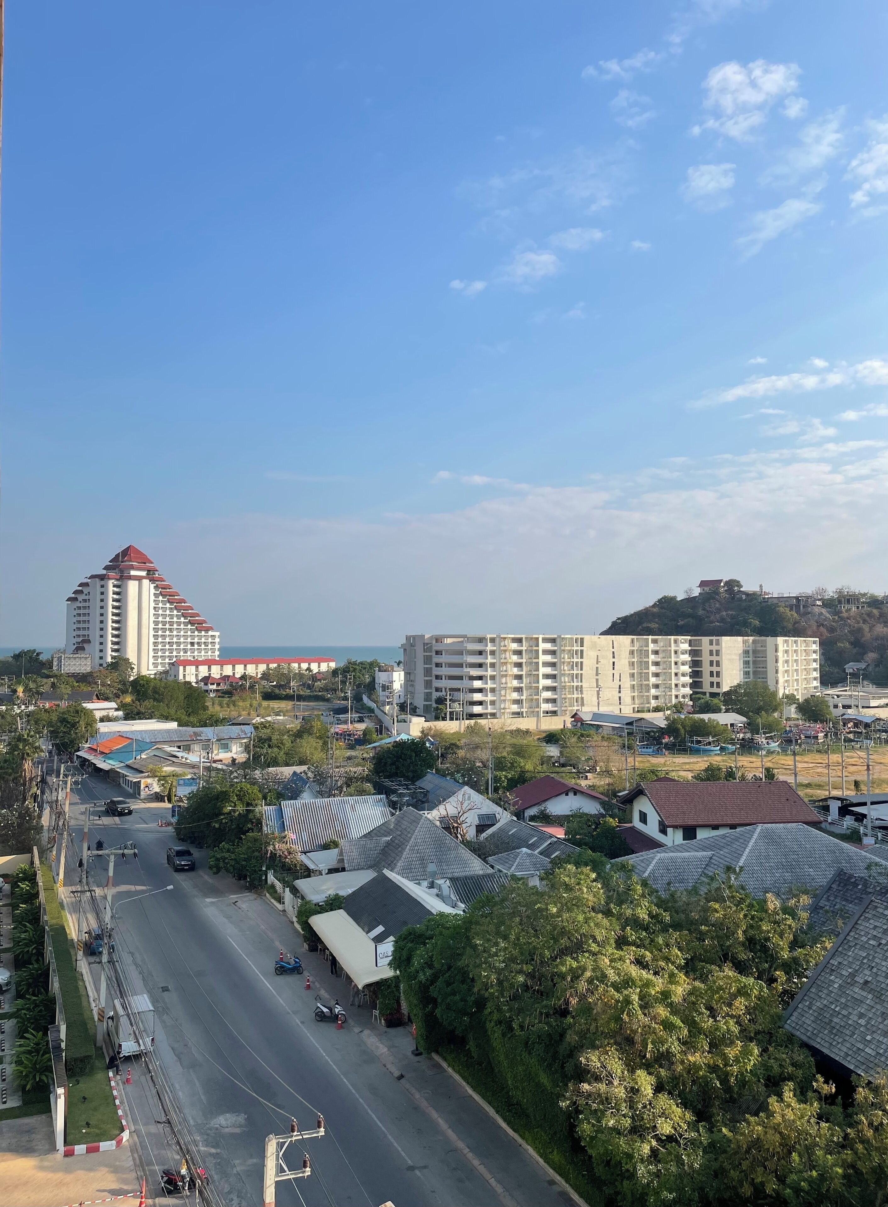 A cityscape with a prominent building with a red roof, a large parking lot, and a clear sky.