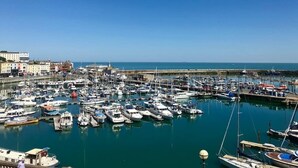 Un puerto deportivo con numerosas embarcaciones amarradas, un cielo despejado y edificios al fondo.