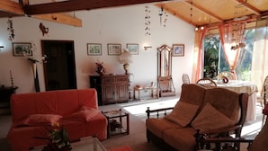 A cozy living room with a red sofa, a wooden armchair, and a glass coffee table. There is a cabinet with decorative items and a small table with a lamp. - Charming chalet  with private pool and around to beaches (Espargo/Santa Maria da Feira)